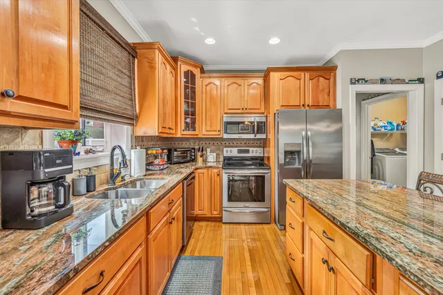 a kitchen with stainless steel appliances granite countertop a refrigerator a stove and a sink with wooden floor