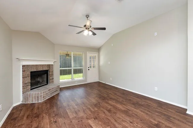 a view of empty room with wooden floor and fireplace
