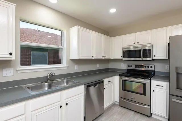 a kitchen with white cabinets appliances and sink