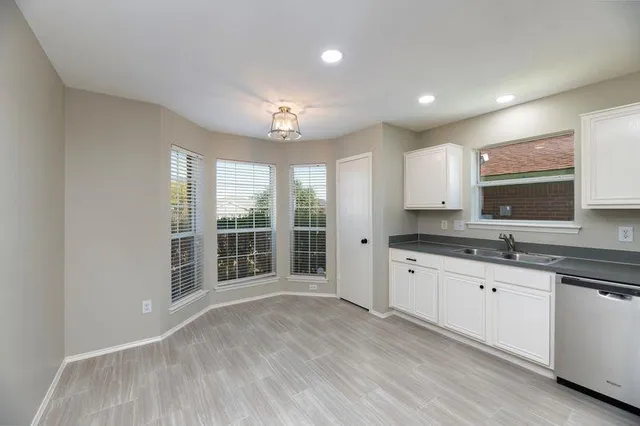 a large kitchen with granite countertop a large window and cabinets