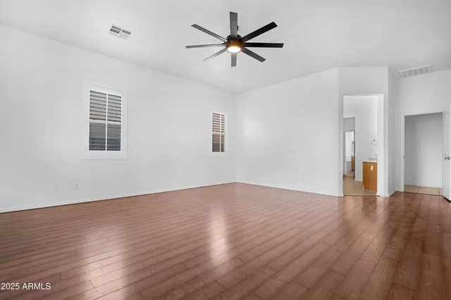an empty room with wooden floor and a ceiling fan