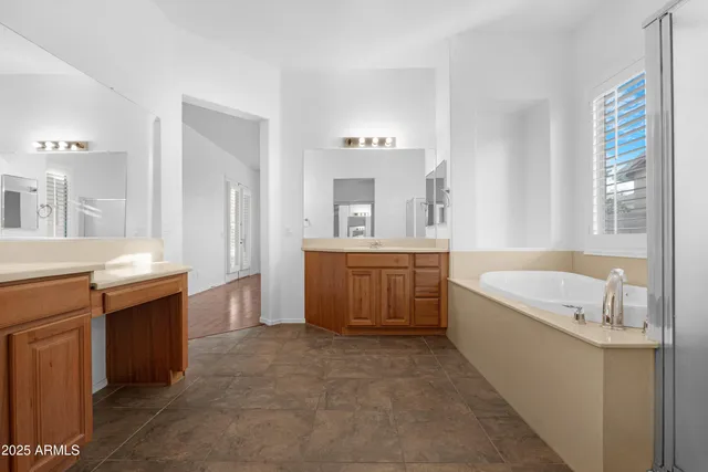 a spacious bathroom with a tub sink and a mirror