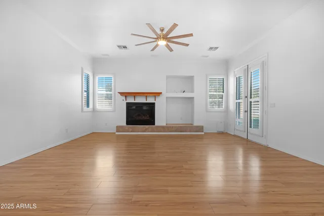 a view of empty room with wooden floor and fan