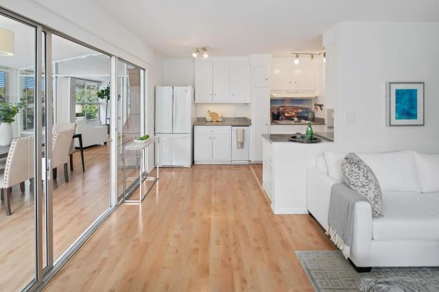 a view of a living room kitchen with stainless steel appliances wooden floor and a large window