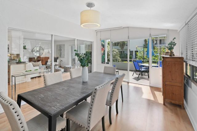 a view of a dining room and livingroom with furniture wooden floor a rug a fireplace and a chandelier