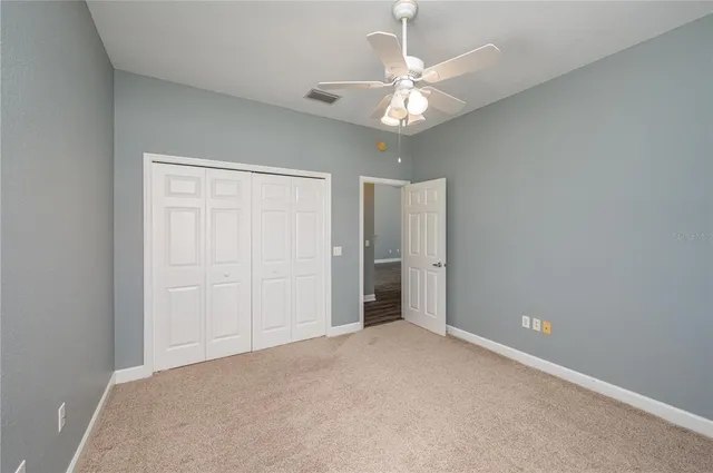 an empty room with a chandelier fan and view of bathroom