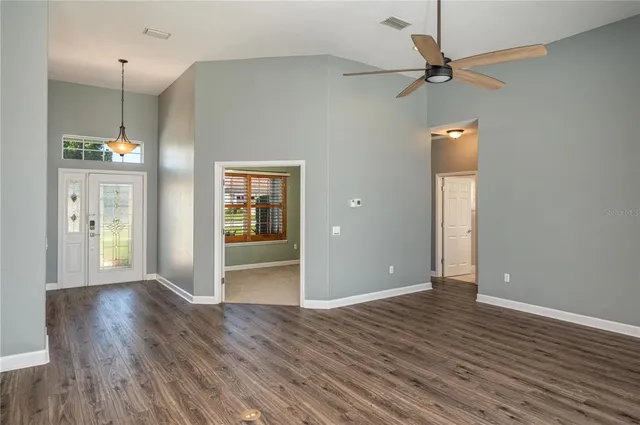 a view of an empty room with wooden floor and a ceiling fan