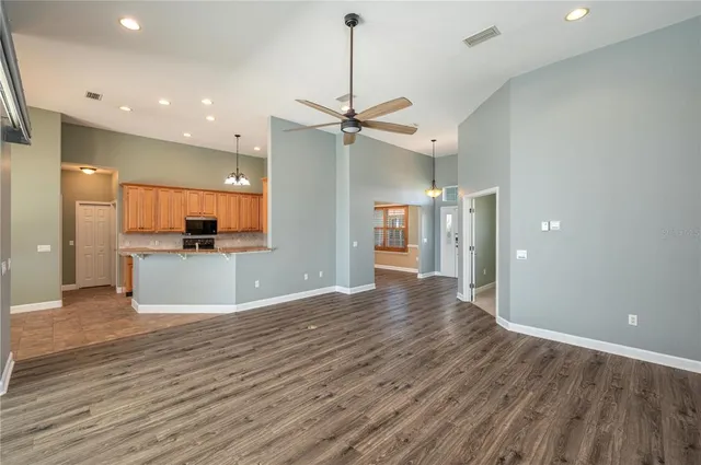 a view of an empty room with kitchen and a window