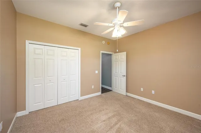 an empty room with a chandelier fan and closet area