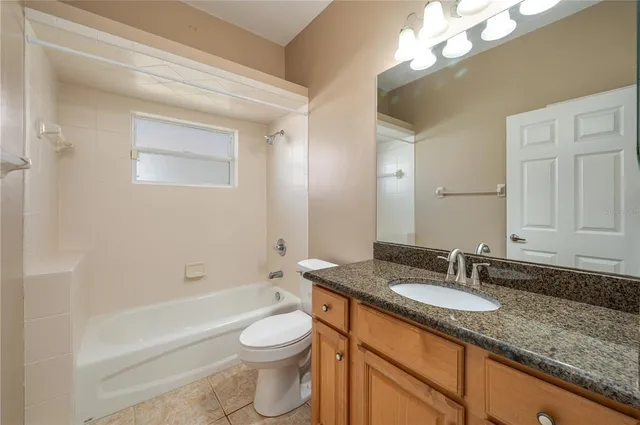 a bathroom with a granite countertop sink mirror vanity toilet and bathtub