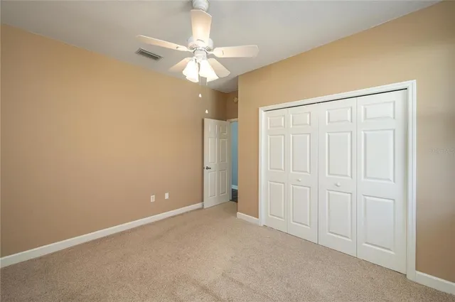 an empty room with a chandelier fan and closet area