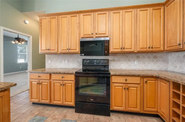 a kitchen with granite countertop wooden cabinets and a stove top oven