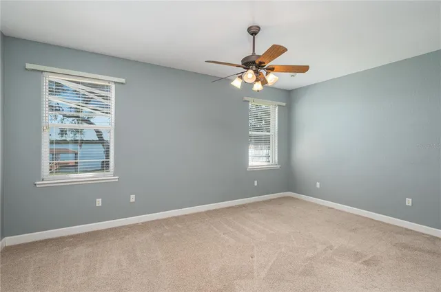 an empty room with windows and fan