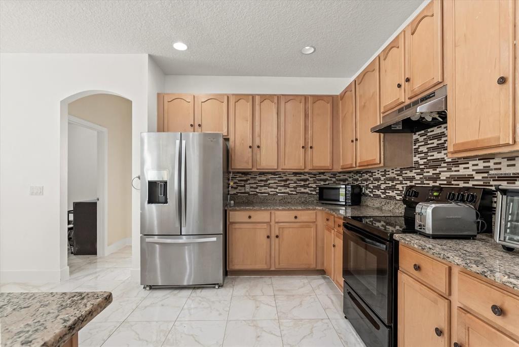 871 Blairmont Lane Lake Mary, FL 32746 - Photo 16 of 56 a kitchen with granite countertop a refrigerator a sink a stove and cabinets