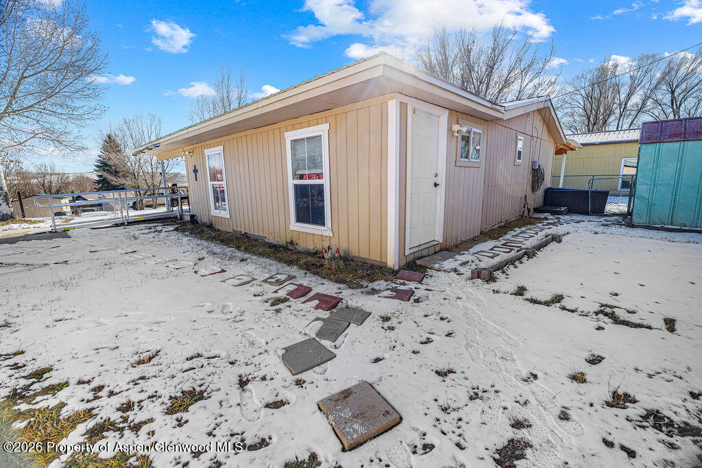 1464 Sage Street Craig, CO 81625 - Photo 32 of 47 a front view of a house with a dirt road and covered with snow