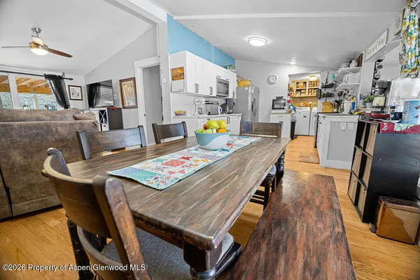 a living room with stainless steel appliances furniture dining table and wooden floor