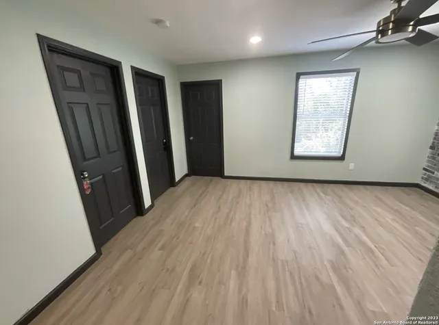 an empty room with wooden floor and windows