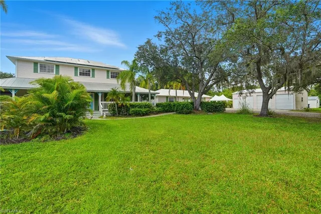 a view of house in front of a big yard with large trees