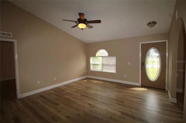 a view of empty room with wooden floor and fan