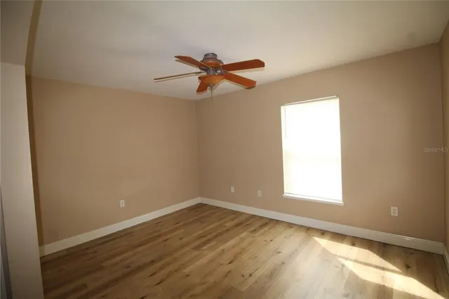 a view of empty room with wooden floor and fan