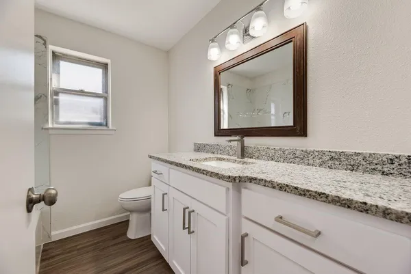 a bathroom with a granite countertop toilet sink and mirror