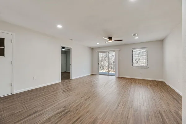 an empty room with wooden floor and windows