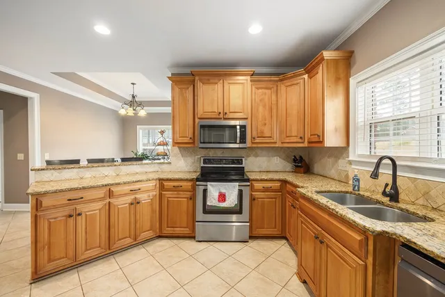 a kitchen with stainless steel appliances granite countertop a stove a sink dishwasher and a refrigerator