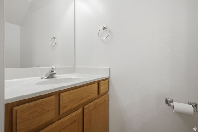 794 East 950 S Street Provo, UT 84606 - Photo 22 of 28 Bathroom vanity featuring a light wood-finish cabinet with panel doors, a white countertop with an integrated sink, and a chrome single-handle faucet