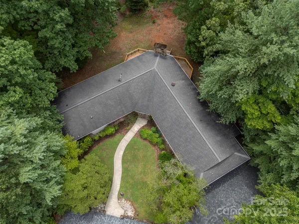 an aerial view of a house with a yard and trees all around
