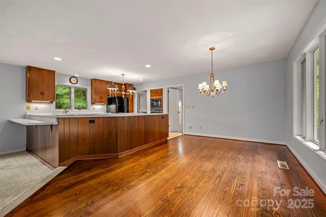 a view of a kitchen with kitchen island wooden floor and stainless steel appliances