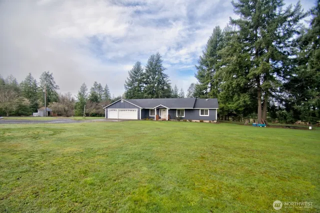 a view of a house with a yard and large trees