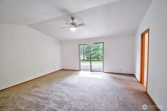 an empty room with windows and chandelier fan