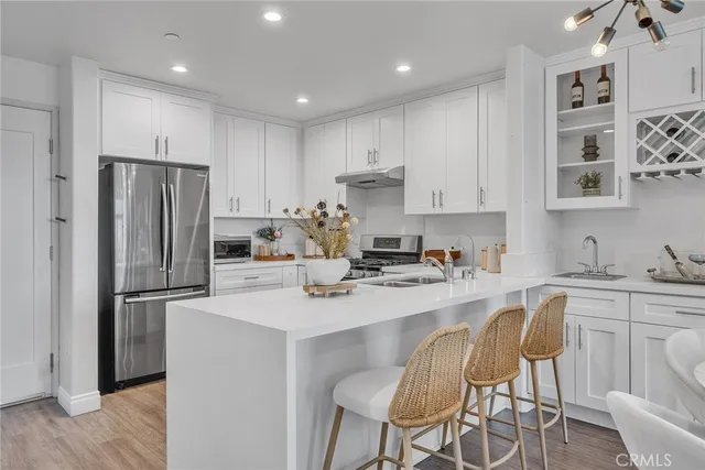 a kitchen with stainless steel appliances a dining table chairs and refrigerator