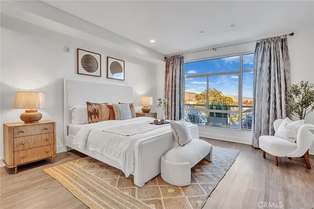 a bedroom with a bed a couch and potted plant on the dresser