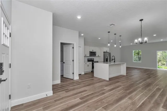 a view of kitchen with kitchen island white cabinets and stainless steel appliances
