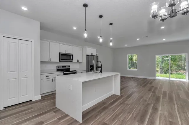 a kitchen with stainless steel appliances a stove top oven a sink a window and cabinets