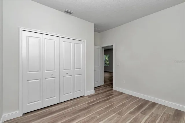 a view of an empty room with closet and wooden floor