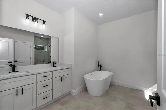 a spacious bathroom with a double vanity sink a mirror and a bathtub