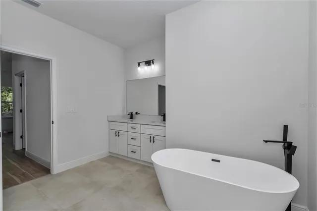 a spacious bathroom with a tub sink and mirror