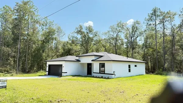 a front view of a house with yard plants and trees