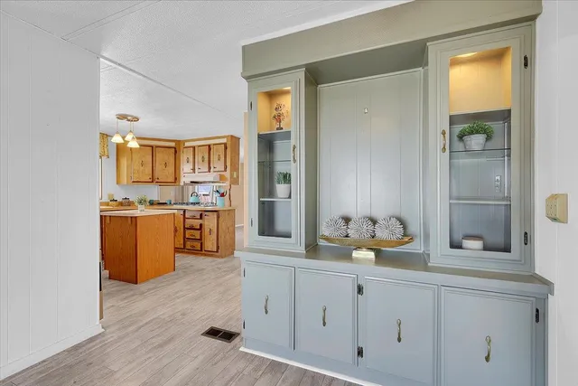 a kitchen with stainless steel appliances granite countertop a refrigerator a sink dishwasher a dining table and chairs with wooden floor