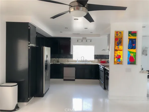 a kitchen with stainless steel appliances kitchen island granite countertop a refrigerator and a sink