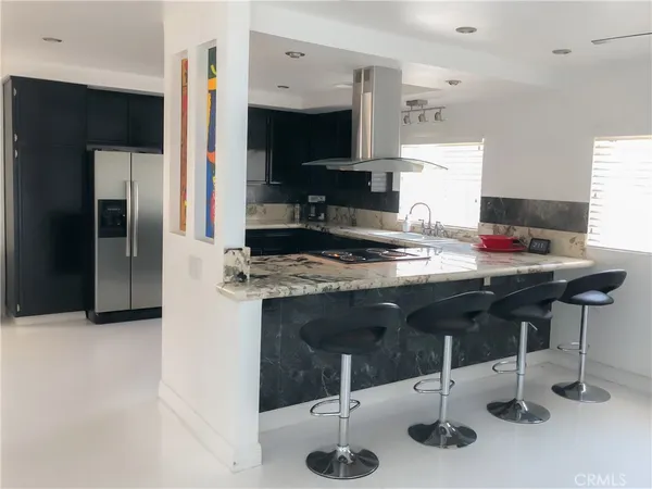a kitchen with stainless steel appliances kitchen island granite countertop a sink refrigerator and cabinets