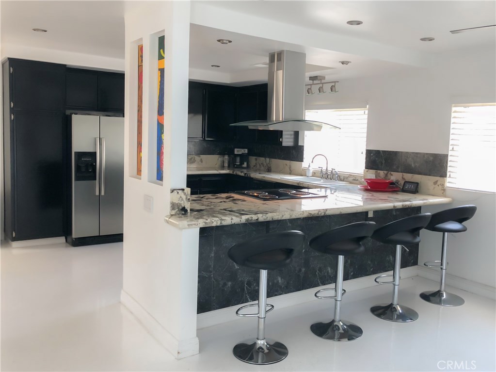 71292 Biskra Road Rancho Mirage, CA 92270 - Photo 9 of 27 a kitchen with stainless steel appliances kitchen island granite countertop a sink refrigerator and cabinets