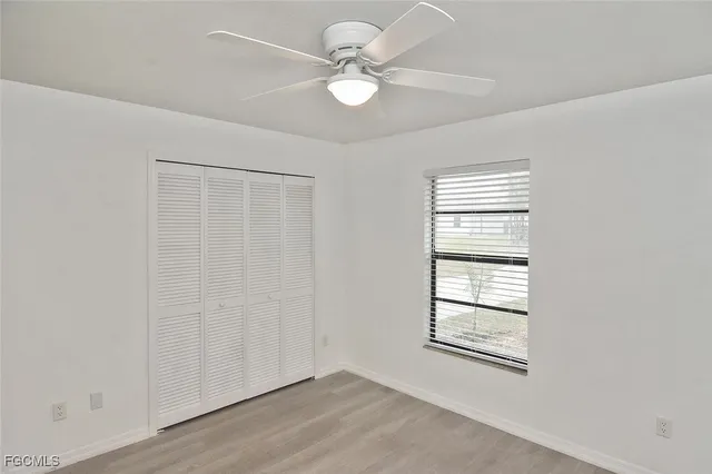 an empty room with windows and fan