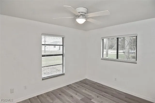 a view of an empty room with a window and wooden floor