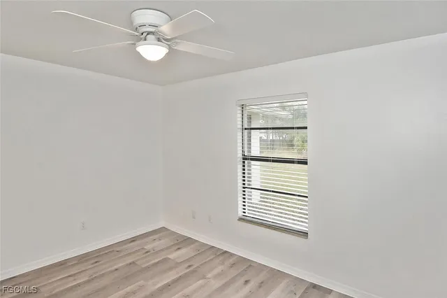 an empty room with windows and fan