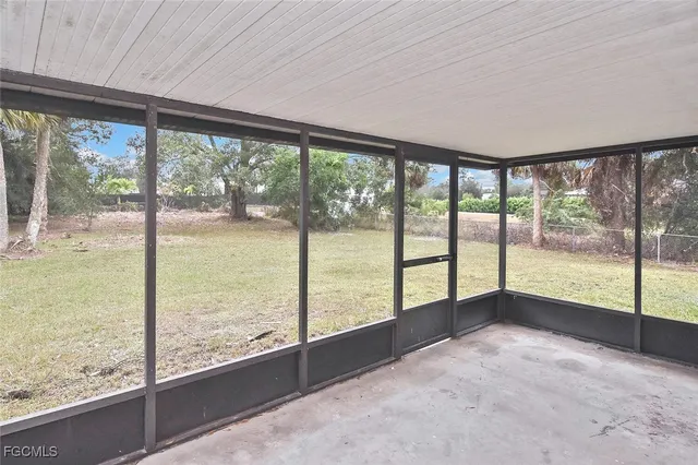 a view of an empty room with wooden floor and a large window