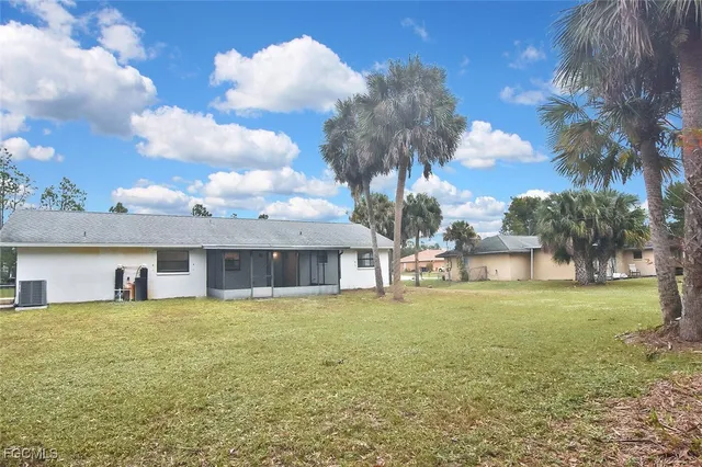 a view of a house with a yard and a large tree