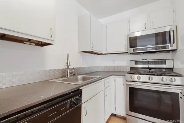 a kitchen with stainless steel appliances a stove microwave and sink